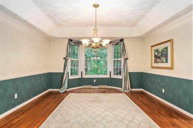 spare room featuring a chandelier, dark hardwood / wood-style flooring, and a raised ceiling