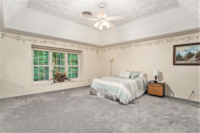 carpeted bedroom featuring a raised ceiling and ceiling fan