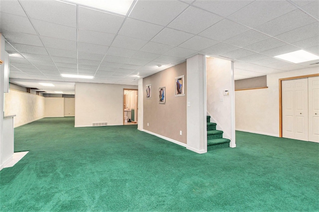 basement with a paneled ceiling and dark carpet