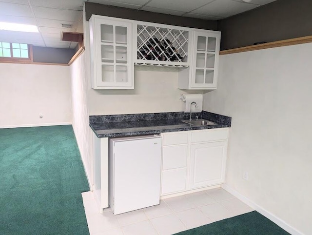 bar featuring sink, fridge, a paneled ceiling, light carpet, and white cabinets