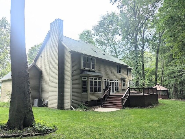 rear view of house with a lawn, central AC unit, and a deck