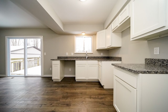 kitchen with dark stone countertops, sink, white cabinets, and dark wood-type flooring