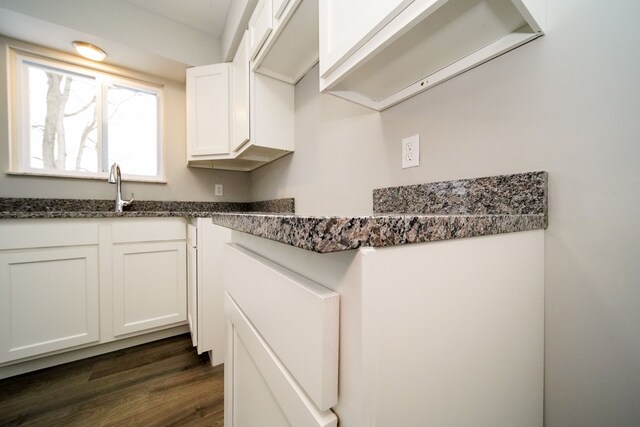 kitchen featuring dark hardwood / wood-style flooring, white cabinetry, sink, and dark stone counters