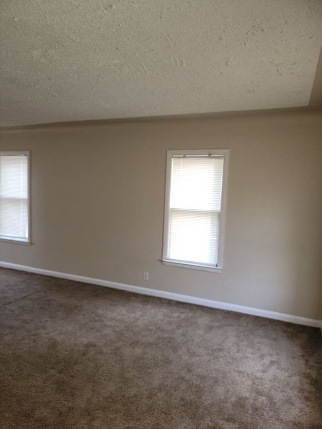 carpeted spare room with a textured ceiling