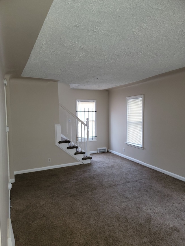 unfurnished living room featuring dark colored carpet