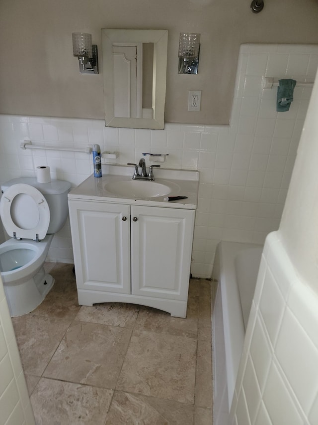 bathroom featuring toilet, tile walls, vanity, and a tub to relax in