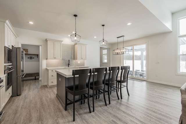 kitchen featuring hanging light fixtures, sink, light hardwood / wood-style flooring, appliances with stainless steel finishes, and a kitchen island