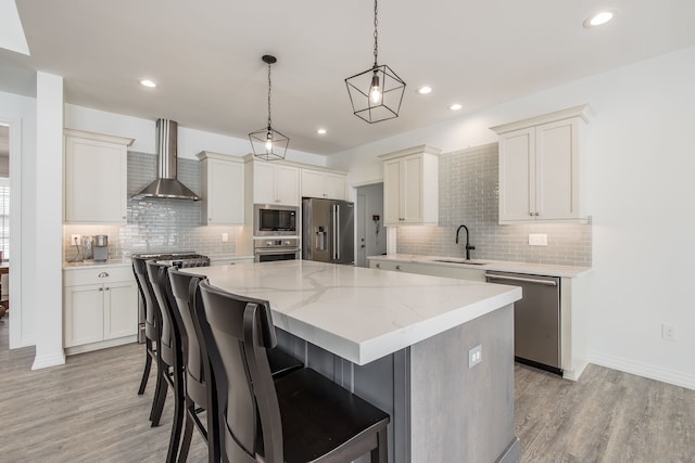 kitchen with wall chimney exhaust hood, stainless steel appliances, sink, pendant lighting, and a kitchen island