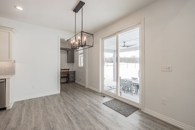 unfurnished dining area with light hardwood / wood-style floors and a notable chandelier