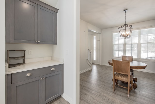 kitchen with gray cabinets, light hardwood / wood-style floors, decorative light fixtures, and an inviting chandelier