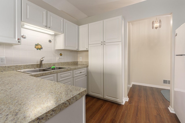 kitchen featuring white cabinetry, sink, hanging light fixtures, dark hardwood / wood-style floors, and backsplash