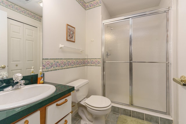 bathroom with tile patterned flooring, vanity, toilet, and a shower with shower door