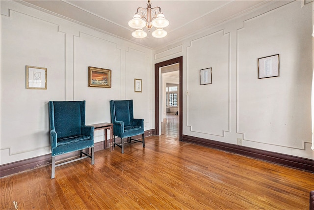 sitting room featuring hardwood / wood-style flooring, an inviting chandelier, and ornamental molding