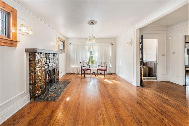 unfurnished living room featuring crown molding, a fireplace, hardwood / wood-style floors, and an inviting chandelier