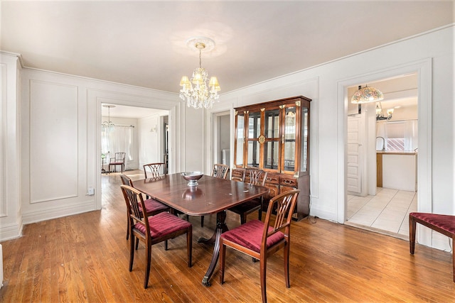 dining room featuring crown molding, a chandelier, and light wood-type flooring