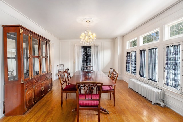 dining area with radiator heating unit, light hardwood / wood-style floors, and an inviting chandelier