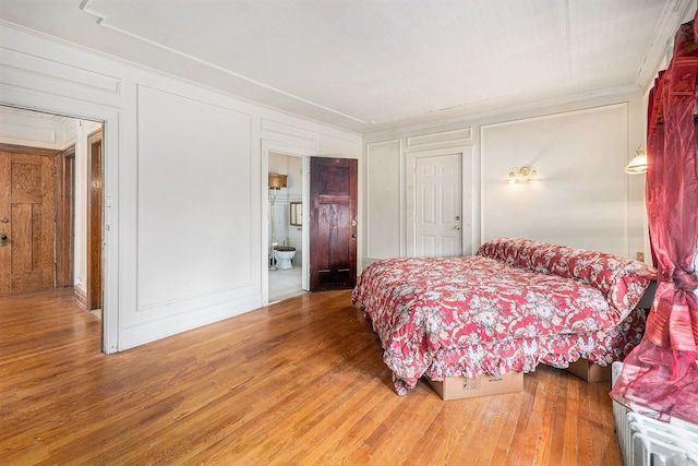 bedroom with ensuite bathroom and hardwood / wood-style flooring