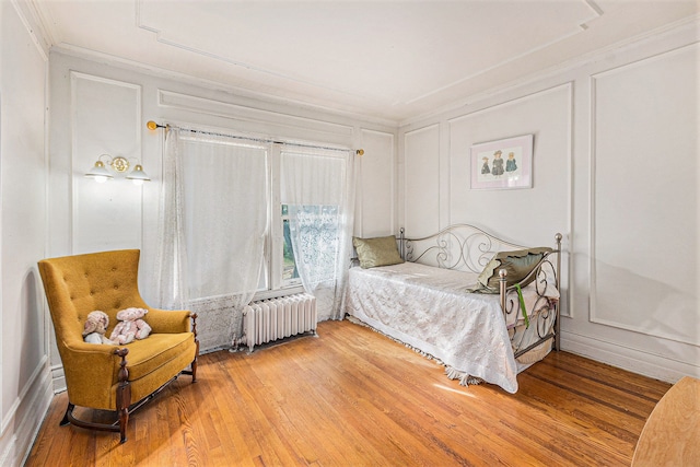 bedroom featuring radiator heating unit, crown molding, and wood-type flooring