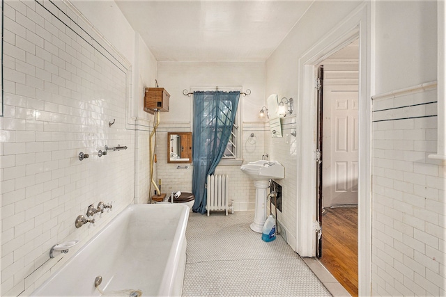 bathroom featuring a tub to relax in, radiator heating unit, tile walls, and tile patterned flooring