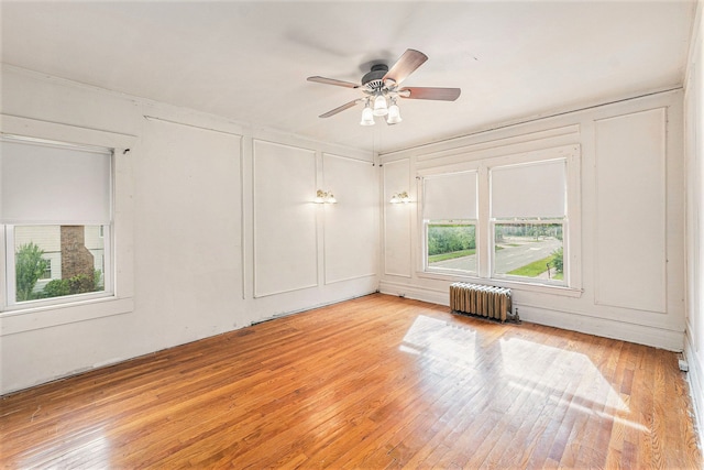 spare room with radiator, ceiling fan, and light hardwood / wood-style floors