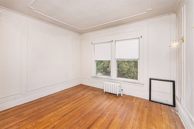 empty room featuring radiator, light hardwood / wood-style floors, and ornamental molding