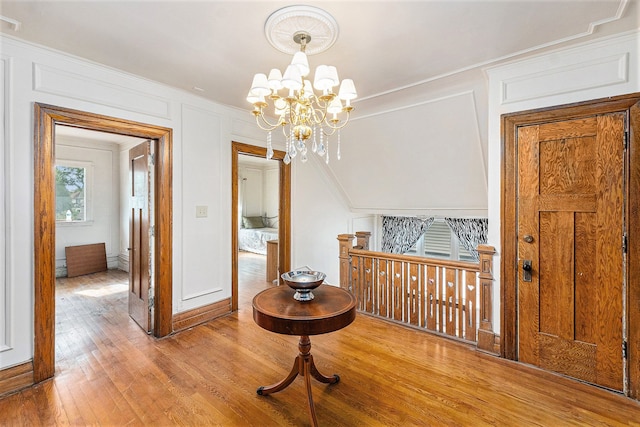 hall with light hardwood / wood-style floors and an inviting chandelier