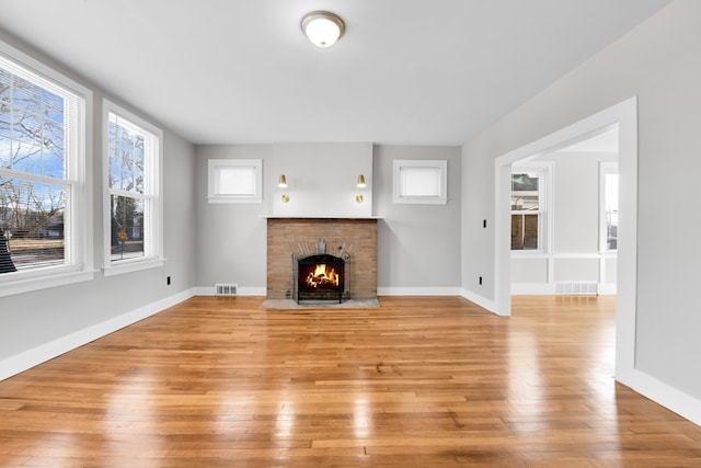 unfurnished living room featuring light hardwood / wood-style flooring and a brick fireplace