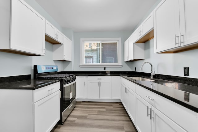 kitchen featuring gas stove, sink, and white cabinets