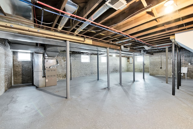 basement featuring heating unit, a wealth of natural light, and brick wall