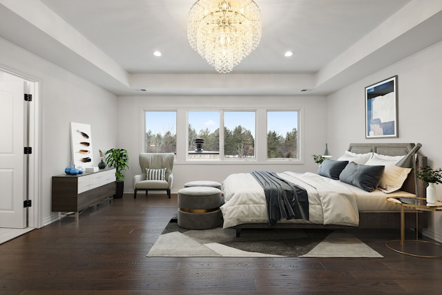 bedroom with a chandelier, a tray ceiling, and dark wood-type flooring