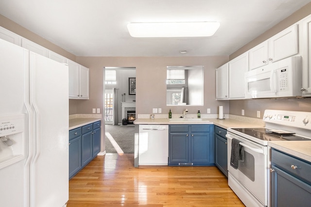 kitchen with blue cabinetry, white appliances, white cabinetry, and sink