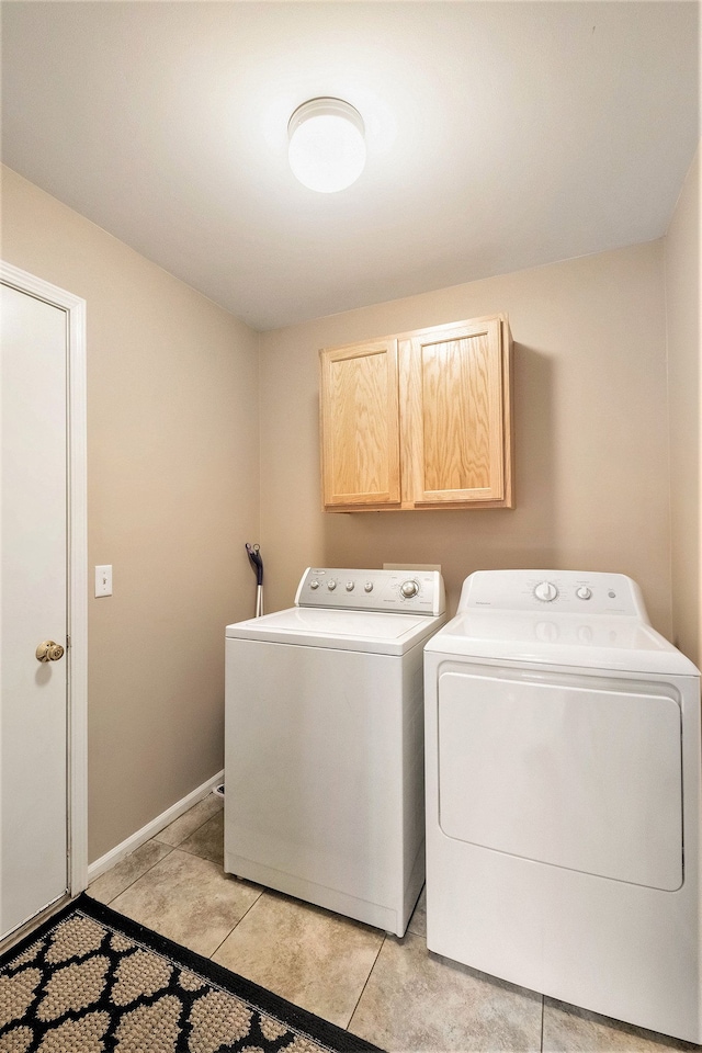 clothes washing area with separate washer and dryer, light tile patterned floors, and cabinets