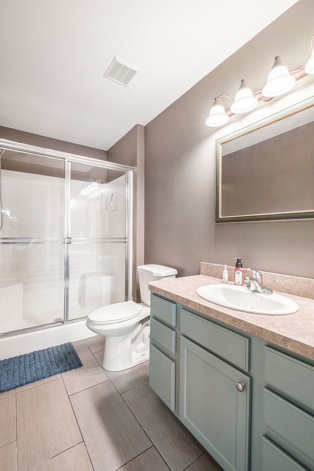 bathroom featuring vanity, a shower with shower door, and toilet