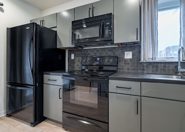 kitchen featuring gray cabinetry, sink, backsplash, light hardwood / wood-style floors, and black appliances