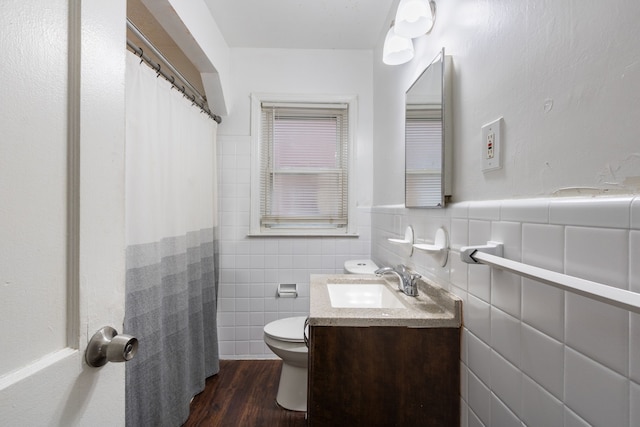 bathroom with toilet, wood-type flooring, vanity, and tile walls