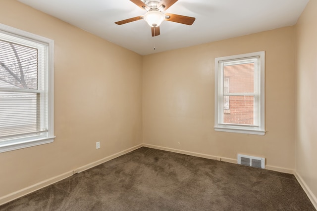 empty room featuring ceiling fan and dark colored carpet