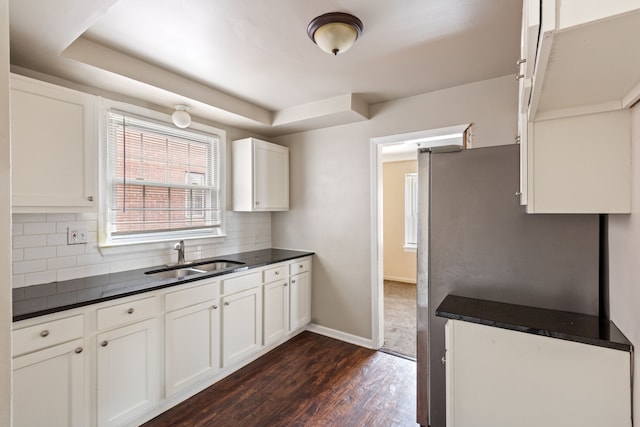 kitchen with white cabinets, dark hardwood / wood-style flooring, stainless steel fridge, sink, and tasteful backsplash