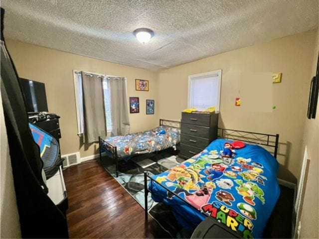 bedroom with a textured ceiling and dark wood-type flooring