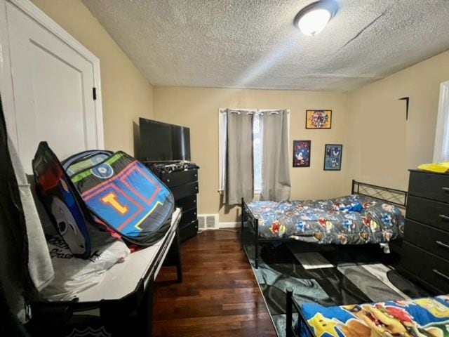 bedroom with a textured ceiling and dark wood-type flooring