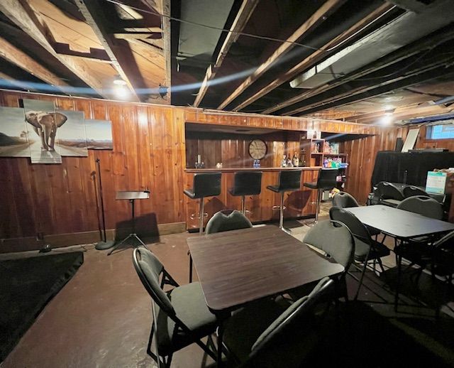 basement featuring wood walls and bar area