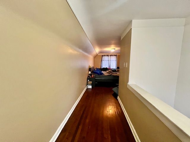 hallway featuring dark hardwood / wood-style flooring and vaulted ceiling