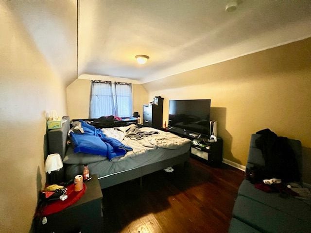 bedroom with dark wood-type flooring and lofted ceiling