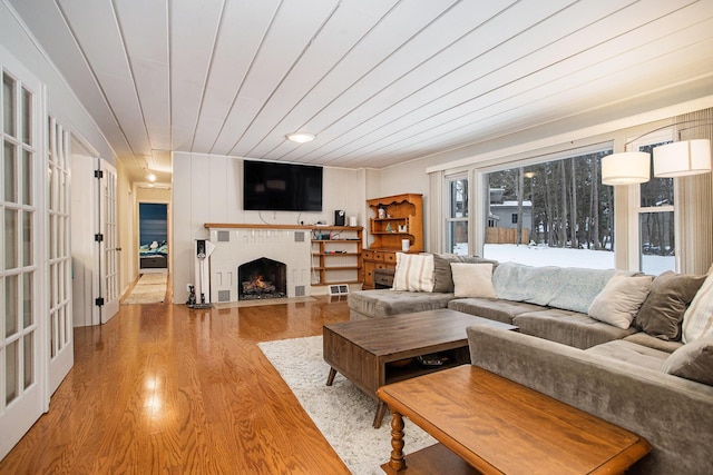 living room with wooden ceiling, light hardwood / wood-style flooring, and a brick fireplace