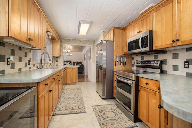 kitchen with sink, tasteful backsplash, kitchen peninsula, stainless steel appliances, and a chandelier