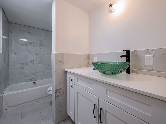 full bathroom with vanity, tile walls, tile patterned flooring, toilet, and tiled shower / bath