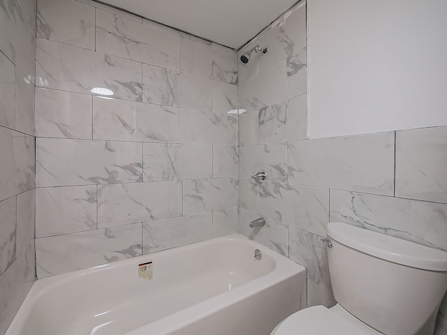 bathroom with tiled shower / bath, tile walls, and toilet