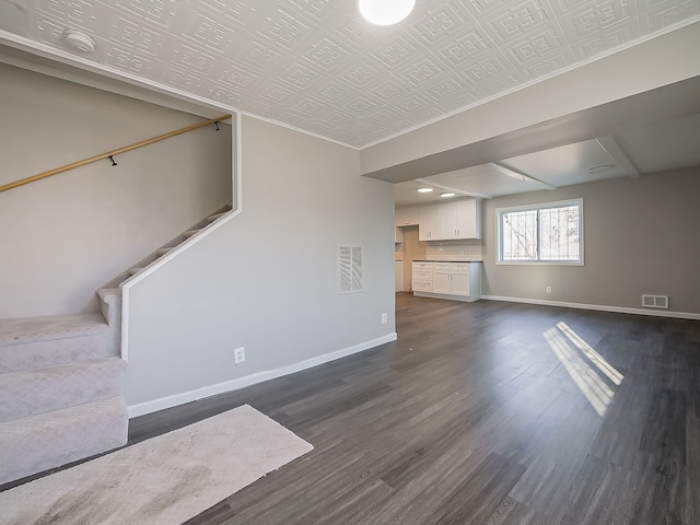 unfurnished living room featuring crown molding and dark wood-type flooring