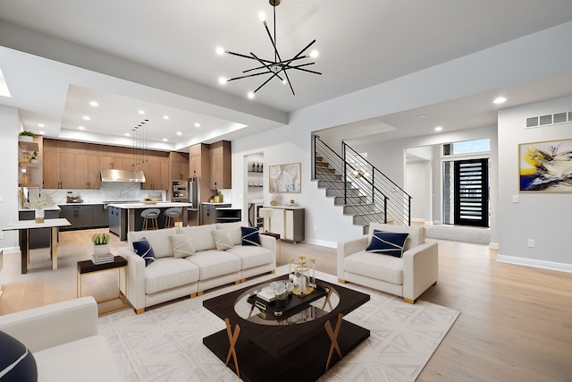 living room featuring a tray ceiling, light hardwood / wood-style flooring, and a chandelier