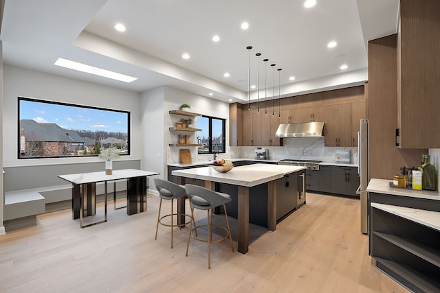 kitchen with light wood-type flooring, dark brown cabinetry, decorative light fixtures, and a kitchen island