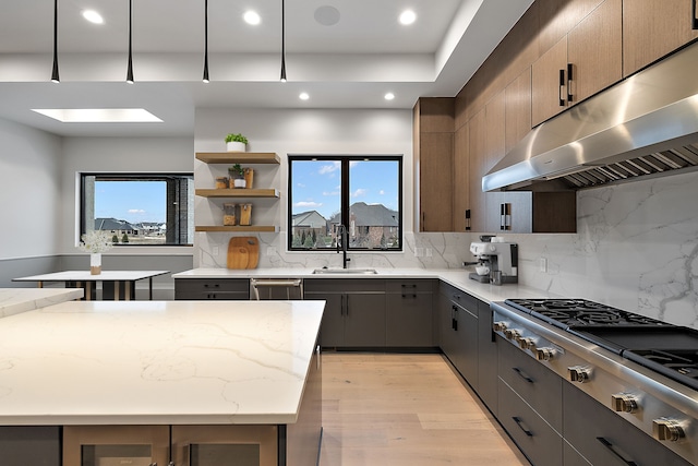 kitchen with a center island, sink, a skylight, light hardwood / wood-style floors, and light stone counters